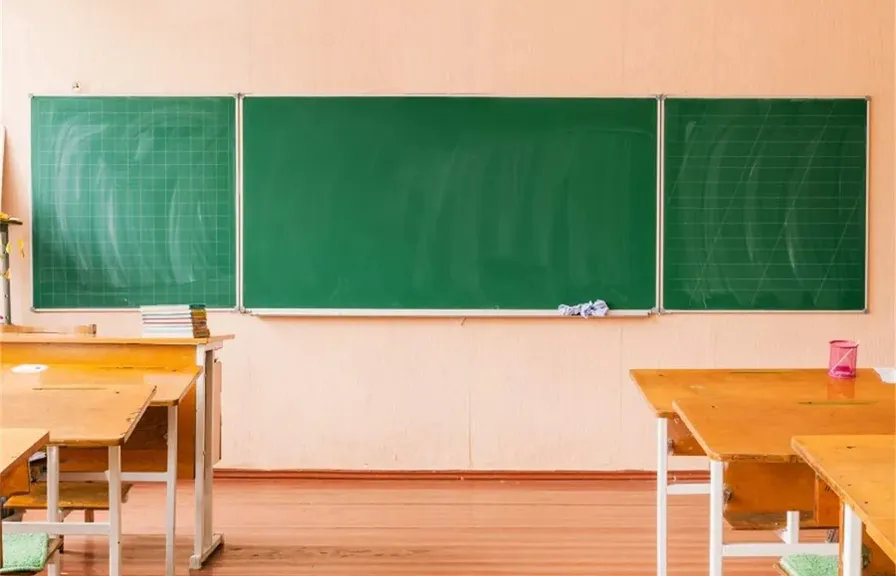 a classroom with a green chalkboard and wooden desks