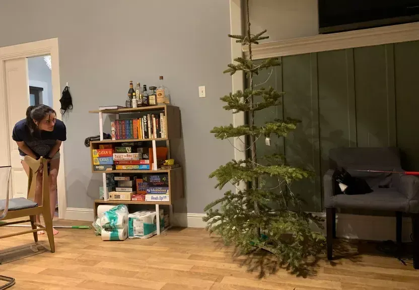 a woman cleaning a room with a christmas tree