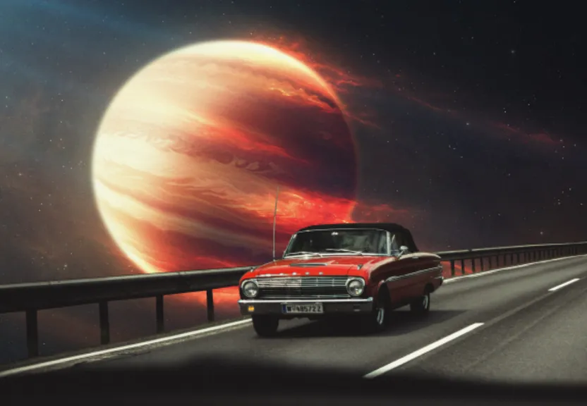 a red car driving down a road next to a red planet