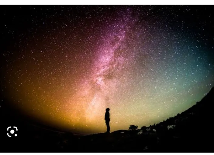 a person standing on top of a hill under a night sky