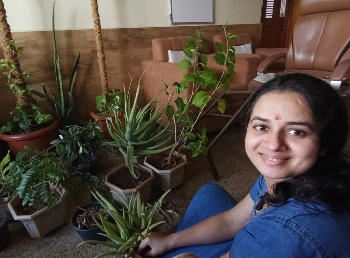 a woman sitting on the floor next to potted plants