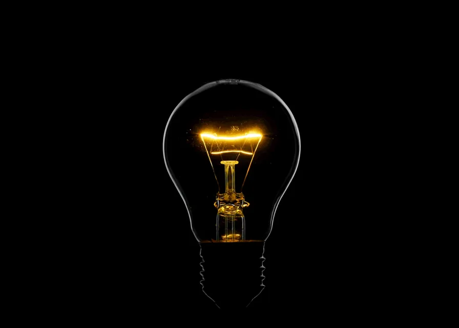 a light bulb that is glowing in the dark. street light, automotive lighting, lamp, light bulb, electricity, facial hair, font, headlamp, fluorescent lamp, audio equipment