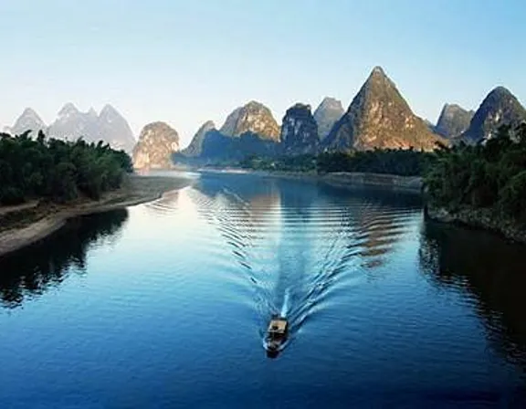 a boat traveling down a river with mountains in the background