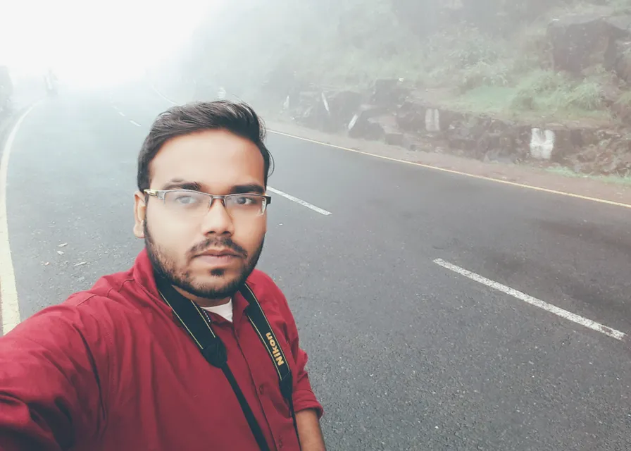 a man taking a selfie on the side of a road in a rocky landscape and light blue sky. replace the man in the background with a rocky landscape and light blue sky