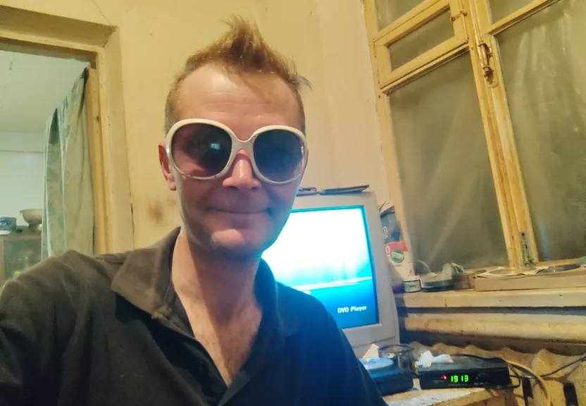 a man with sunglasses on taking a selfie in front of a computer