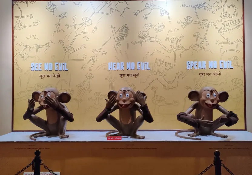 three statues of monkeys sitting in front of a sign add a fourth monkey statue next to the first three