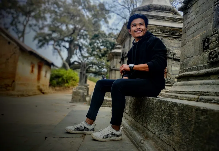 a man sitting on a stone wall next to a building