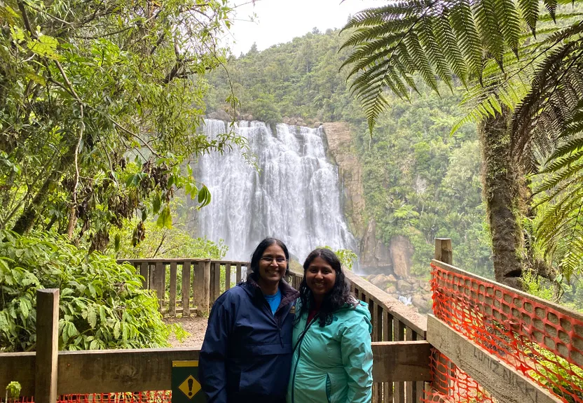 two women standing in front of a waterfall