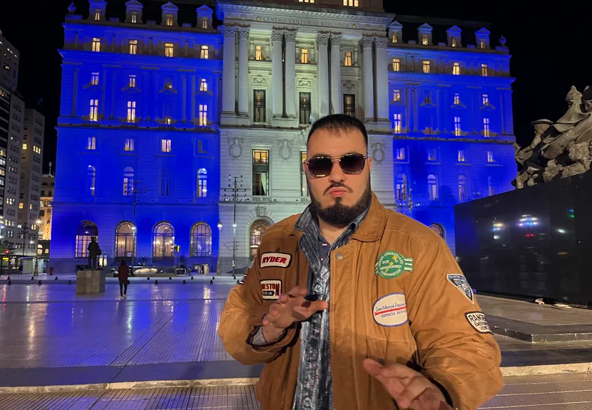 a man in a brown jacket and sunglasses standing in front of a building