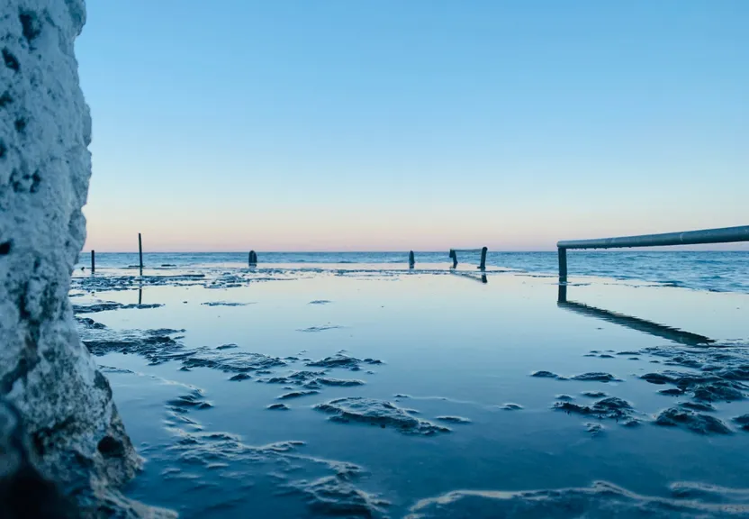 a pool in the middle of a beach covered in ice