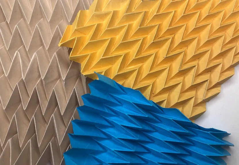 three different colored origami pieces on a wall