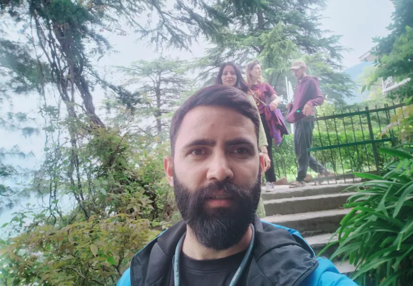 a man with a beard standing in front of some stairs