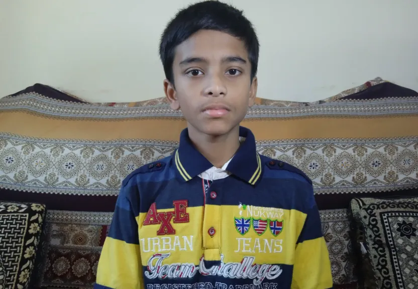 a young boy standing in front of a couch