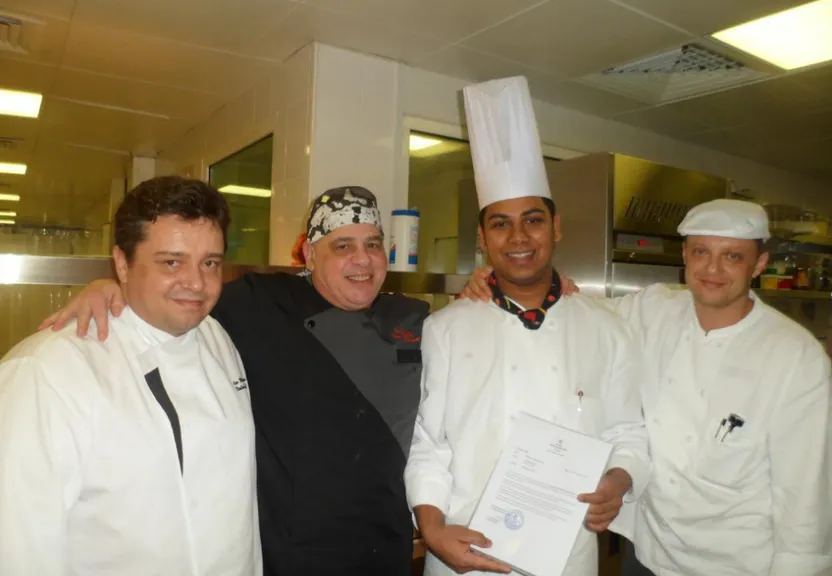 a group of men standing next to each other in a kitchen. Add a close-up of one man's face.