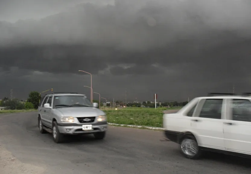 two cars driving down a road under a cloudy sky
