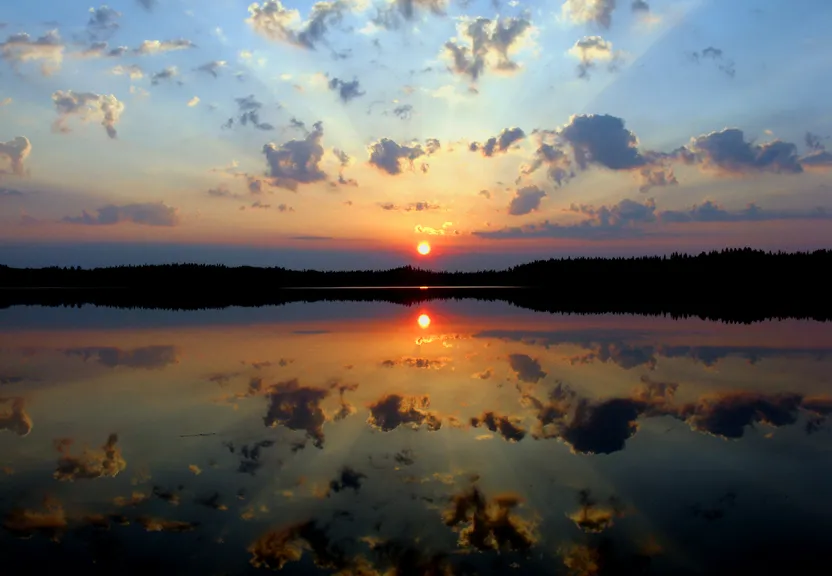 the sun is setting over a calm lake