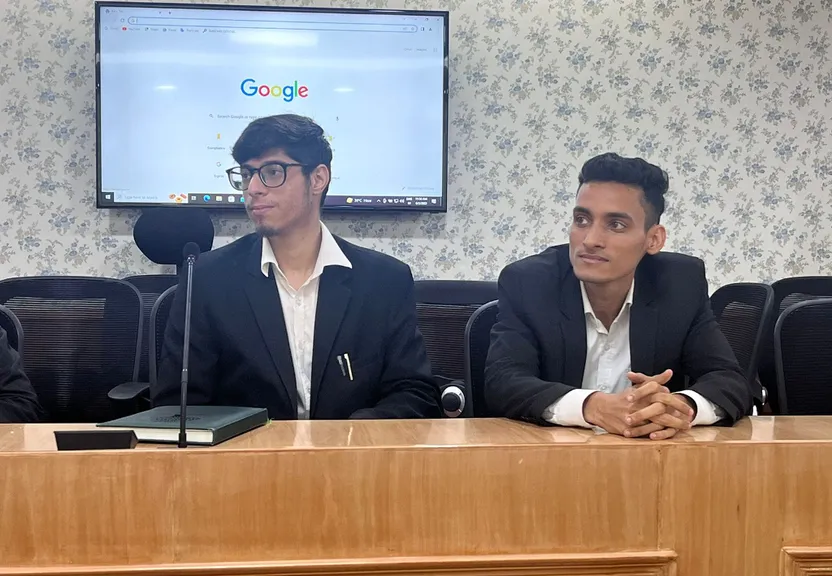 three men sitting at a table in front of a flat screen tv