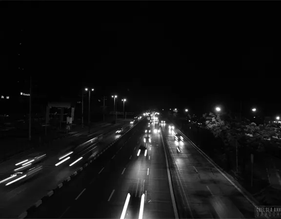 a black and white photo of a highway at night