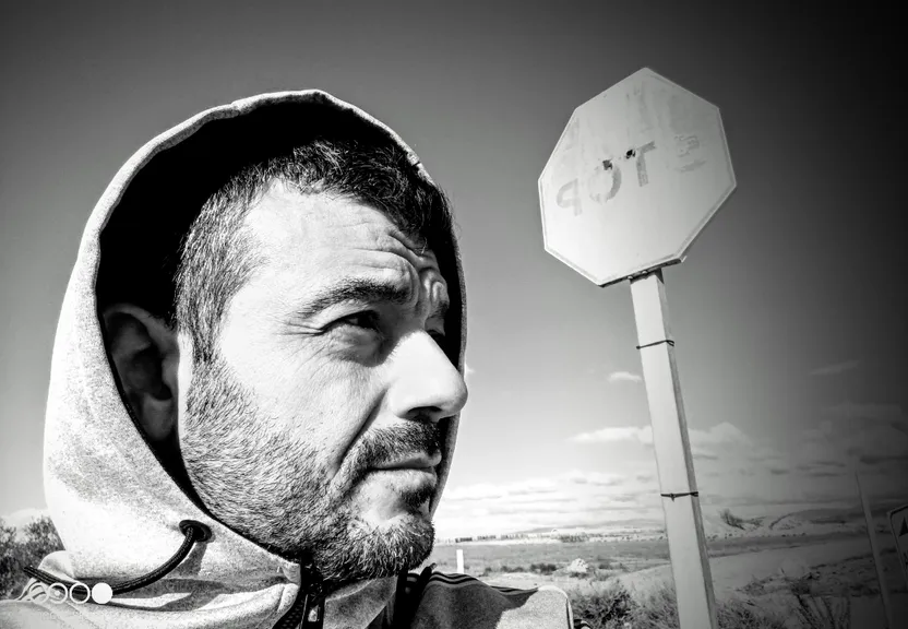 a man in a hoodie standing in front of a stop sign