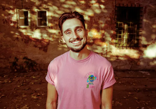 a man in a pink shirt standing in front of a building