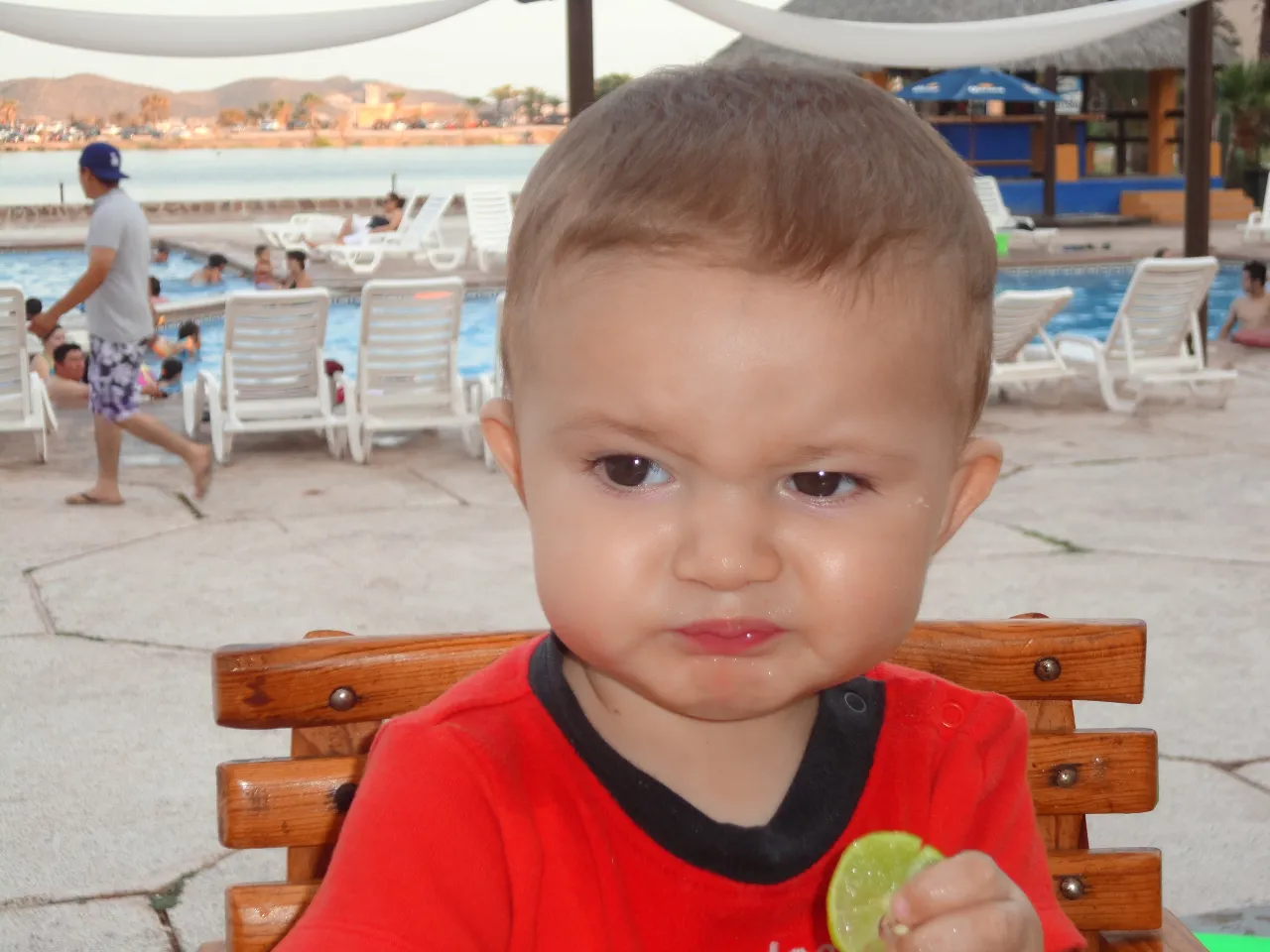 a little boy sitting at a table with a lime in his hand