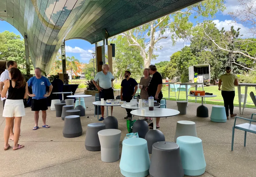 a group of people standing around tables and chairs