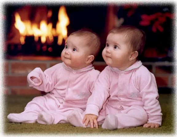 two babies sitting next to each other in front of a fire place. face, cheek, product, sleeve, baby, gesture, happy, rectangle, baby & toddler clothing, toddler