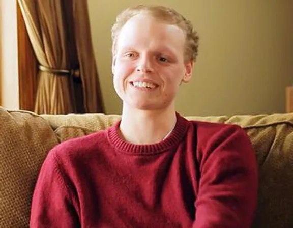 a man in a red sweater sitting on a couch