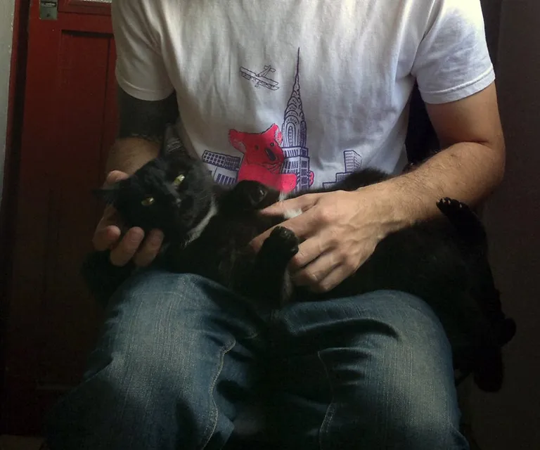 a man holding a black cat in his lap