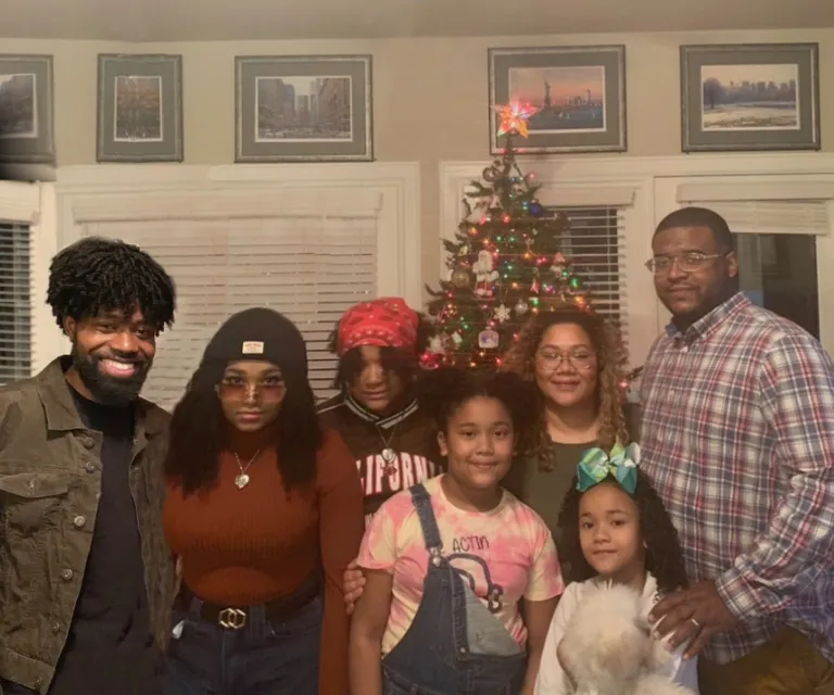 a group of relatives standing in front of a large decoratively lighted Christmas tree