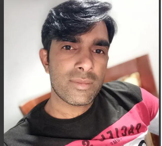 a man with a black hair and a pink shirt
