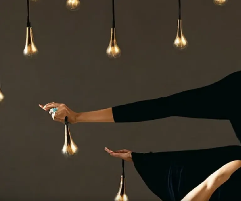 a woman in a black dress is holding a light bulb