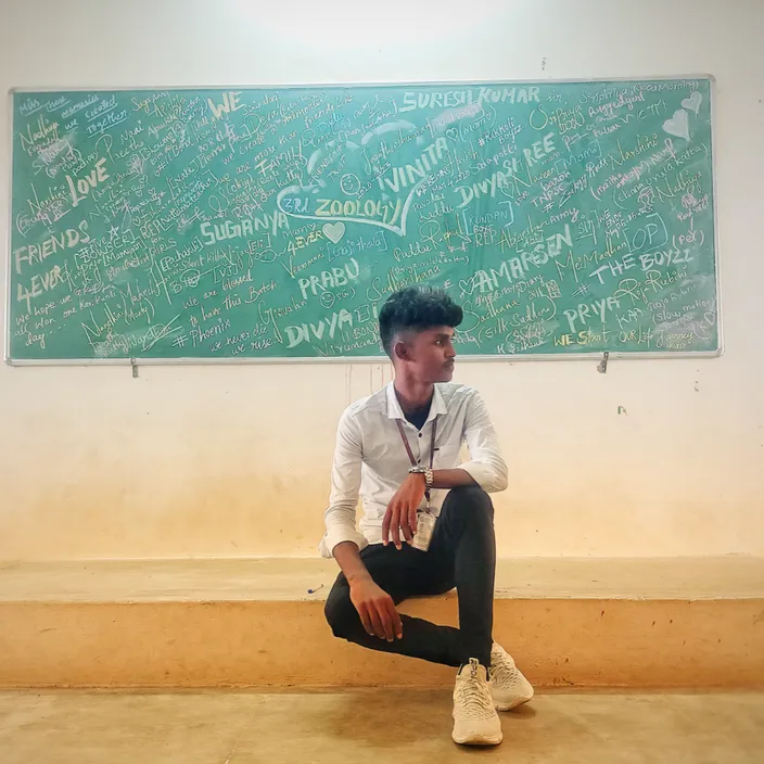 A man sitting on a bench in front of a chalkboard in black and white. in black and white