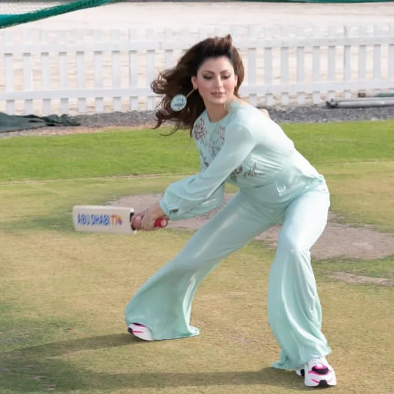 a woman in a blue jumpsuit catching a frisbee. shoe, active pants, sleeve, knee, waist, thigh, grass, sportswear, recreation, leisure