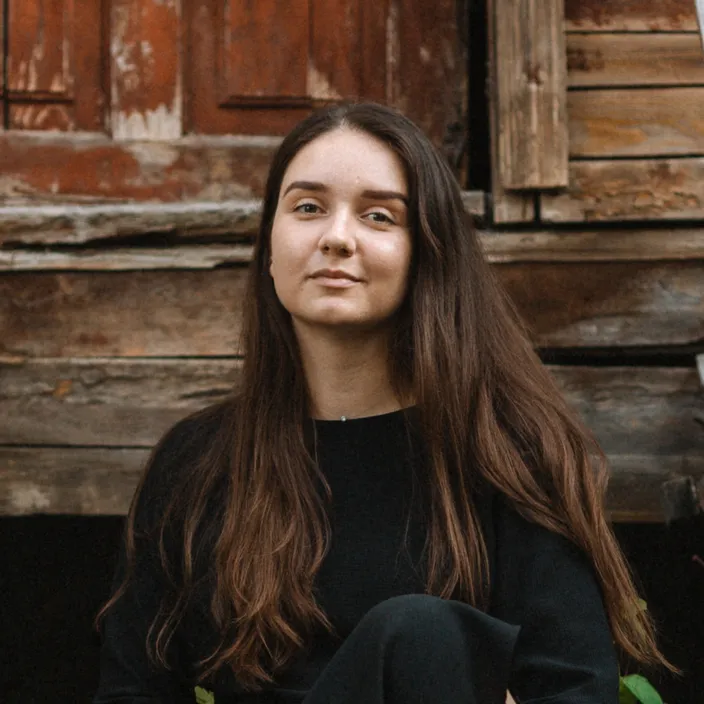 a woman sitting in front of a wooden building