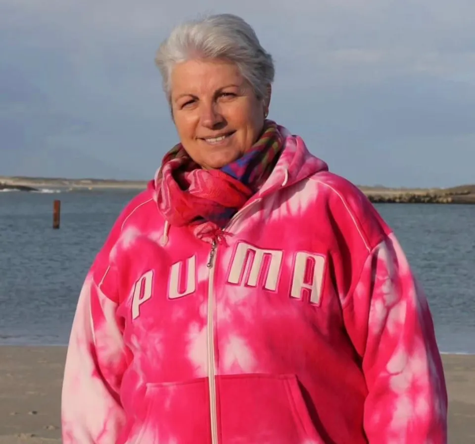 Detailed woman in neon workout outfit doing aerobics on the beach at sunset