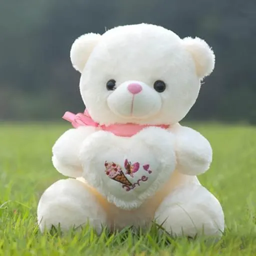 a white teddy bear sitting in the grass
