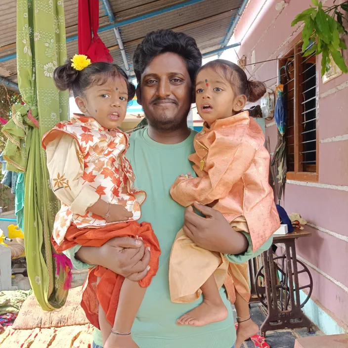 a man holding two small children in his arms