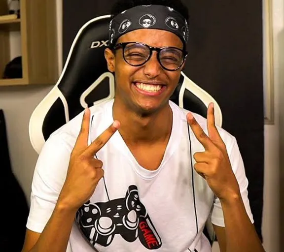 a man wearing glasses sitting in a chair with a peace sign