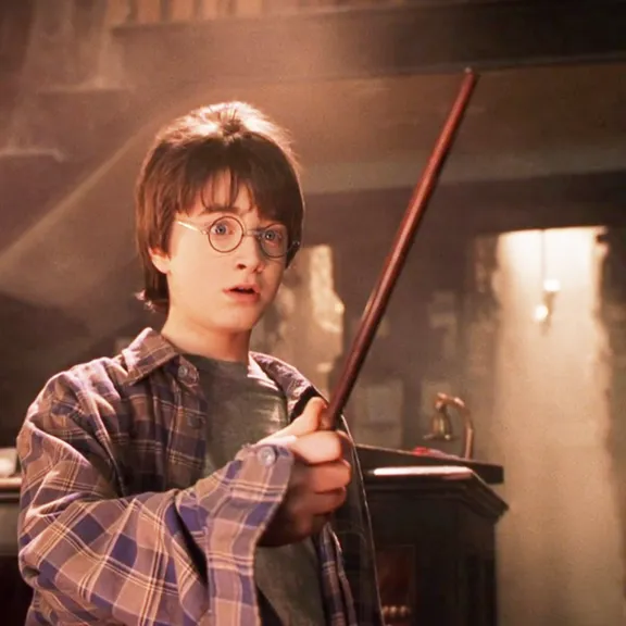 a young boy holding a harry potter wand