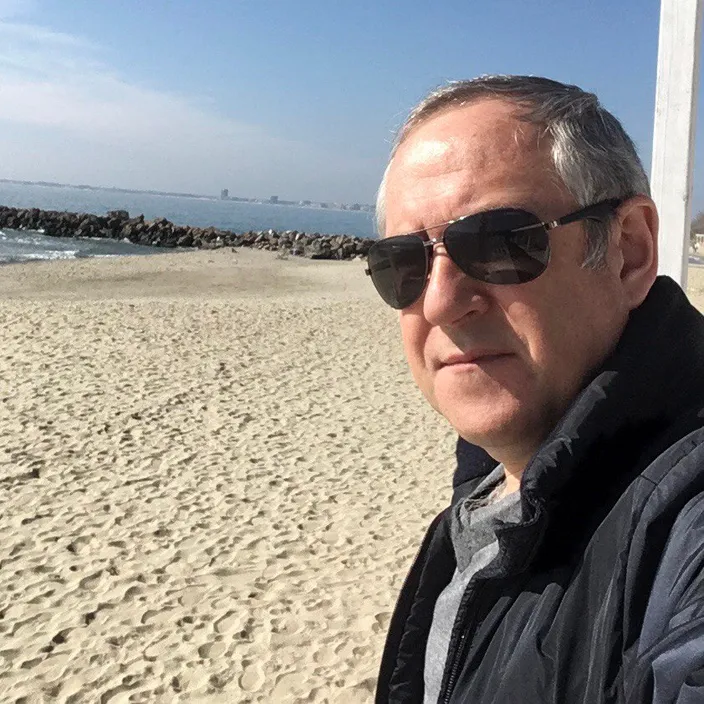 a man wearing sunglasses standing on a beach next to the ocean