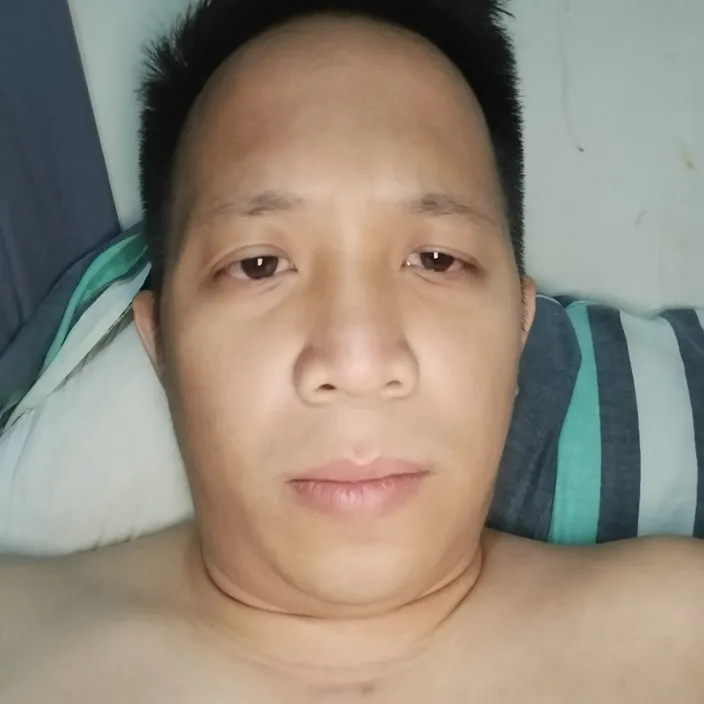 a shirtless man laying on a bed looking at the camera