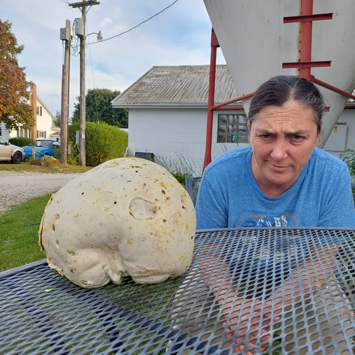 a woman is looking at a large object on a grill
