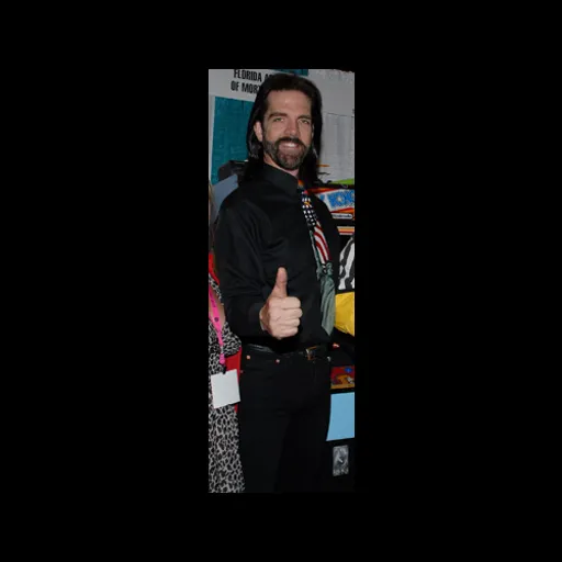 a man giving a thumbs up while standing in front of a wall