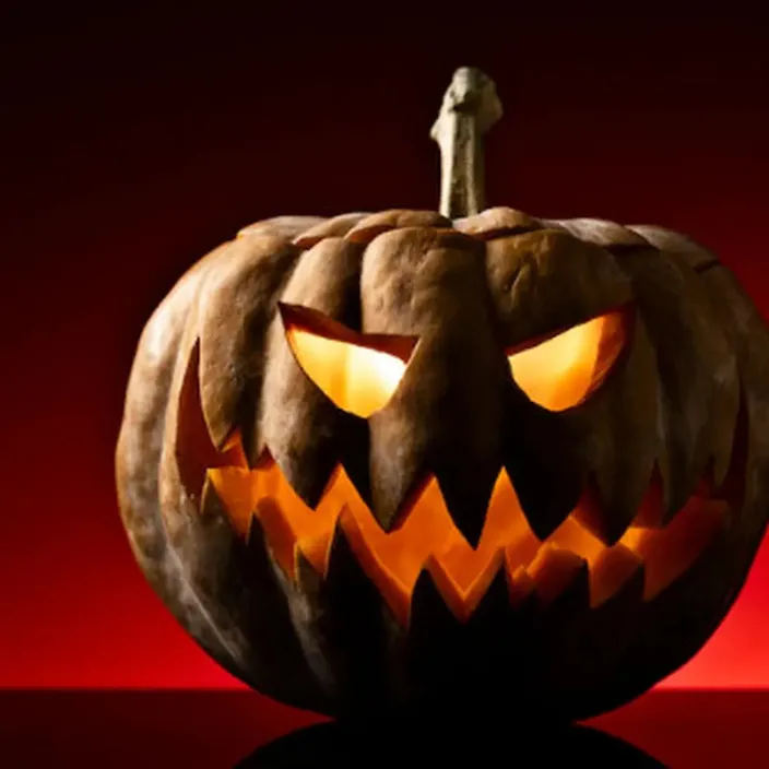 a carved pumpkin with glowing eyes on a table