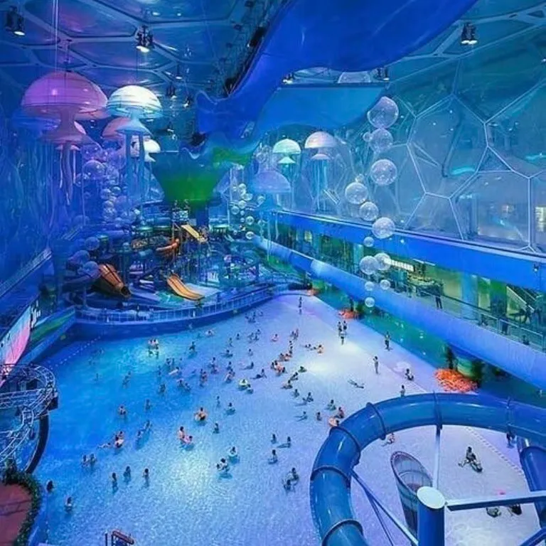 a large indoor water park with a water slide. world, blue, field house, azure, water, art, leisure, fun, electric blue, recreation