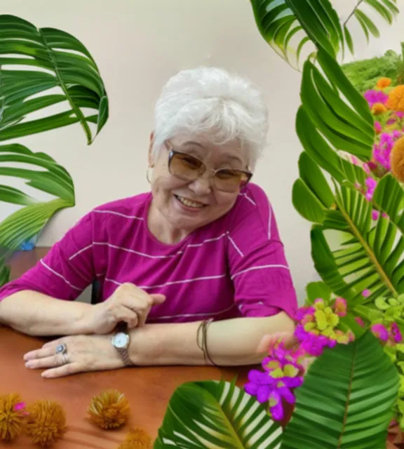 a woman sitting at a table surrounded by plants