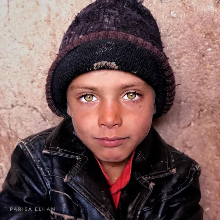 a young boy wearing a black jacket and a black hat