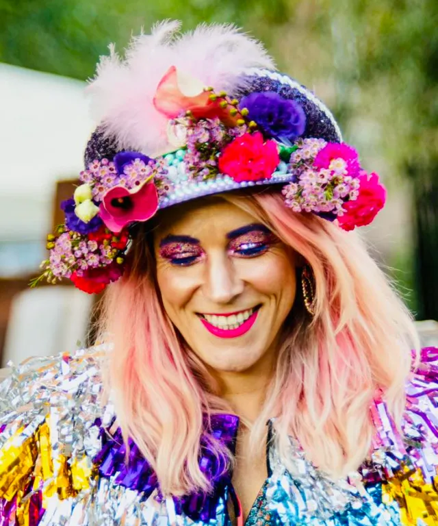 a woman with pink hair wearing a colorful hat