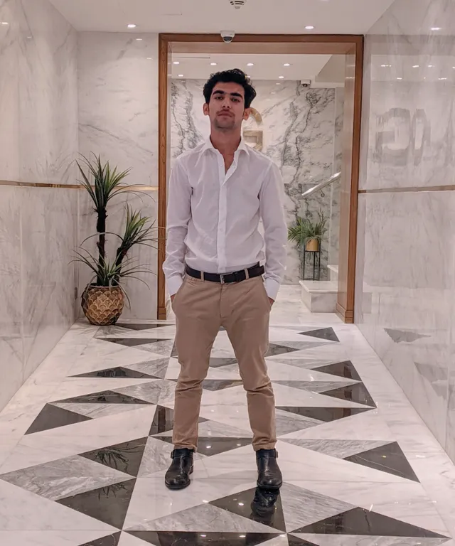 a man in a white shirt and khaki pants standing in an alien hallway. White shirt, black pants, and brown shoes